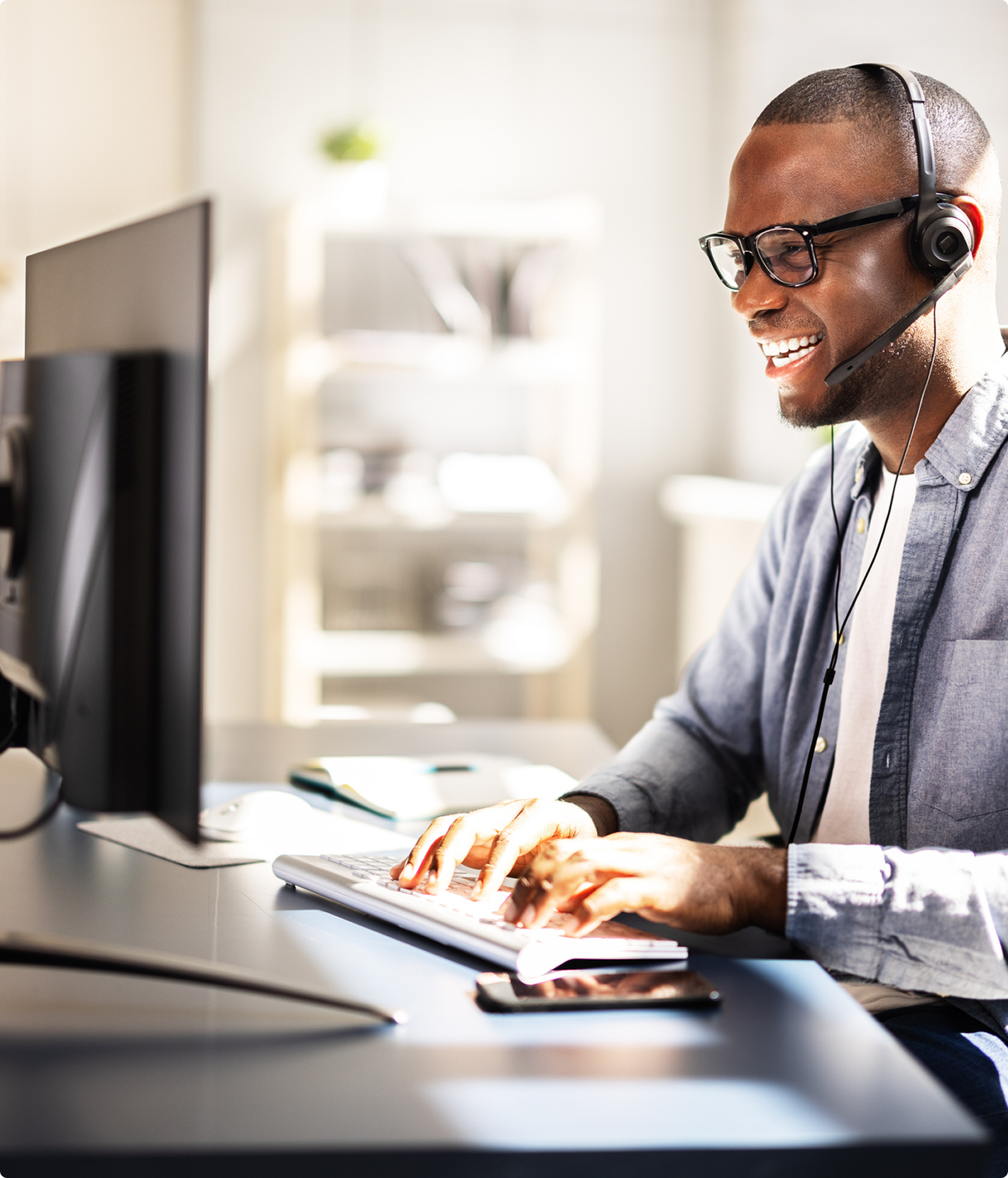 Man smiling while working at computer desk.