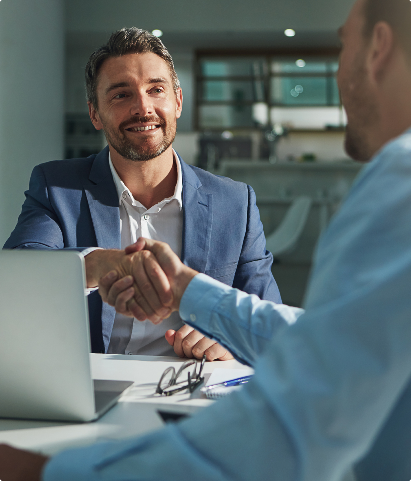 Two men shaking hands in office.