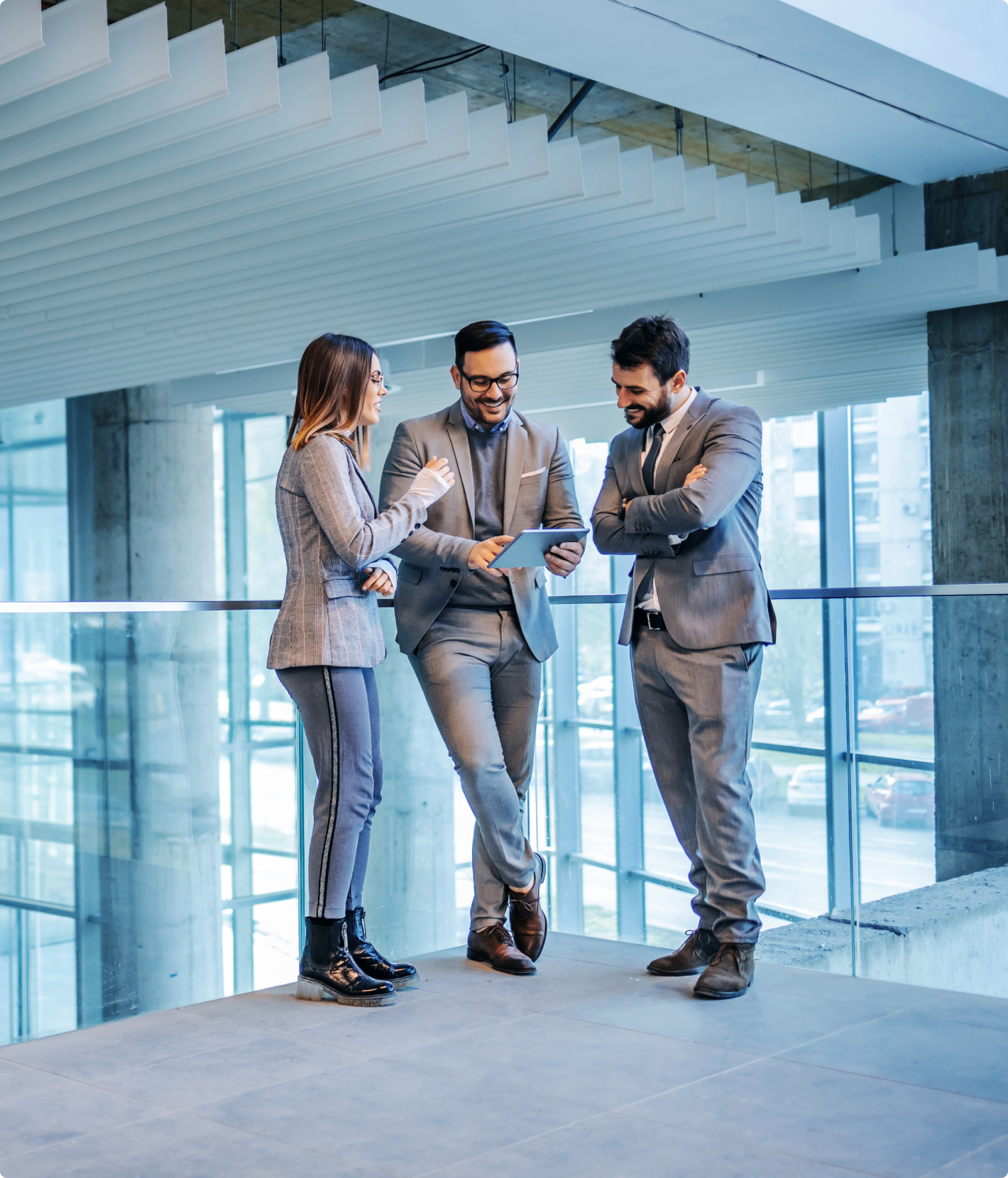 Three colleagues discussing in modern office building.