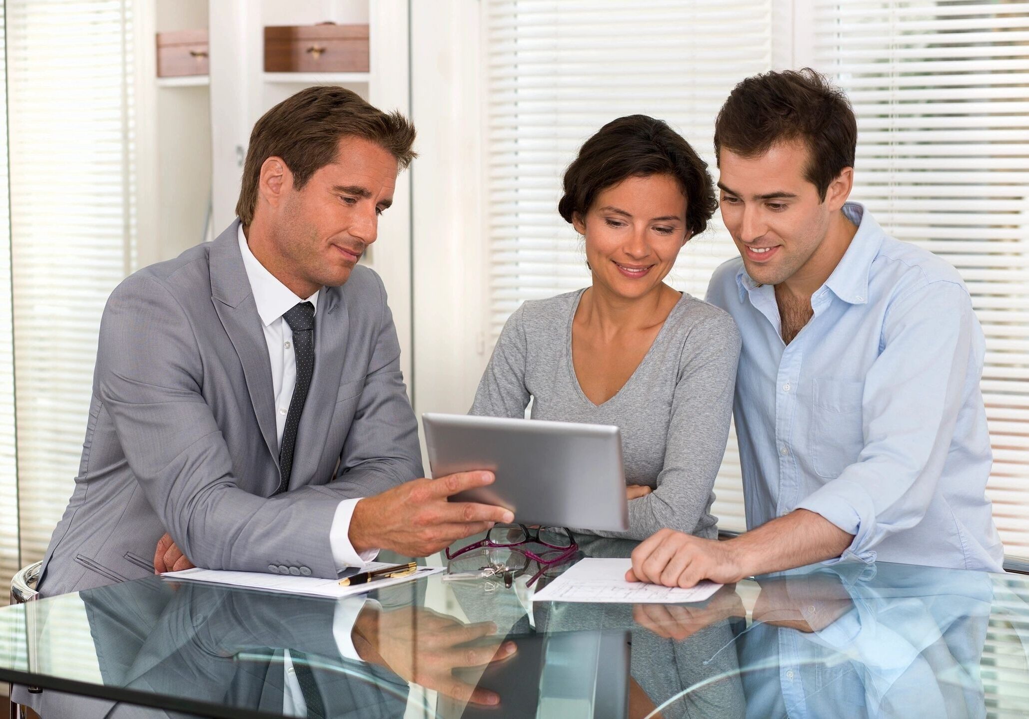 fm=f_284 Three people sitting at a table looking at a tablet.